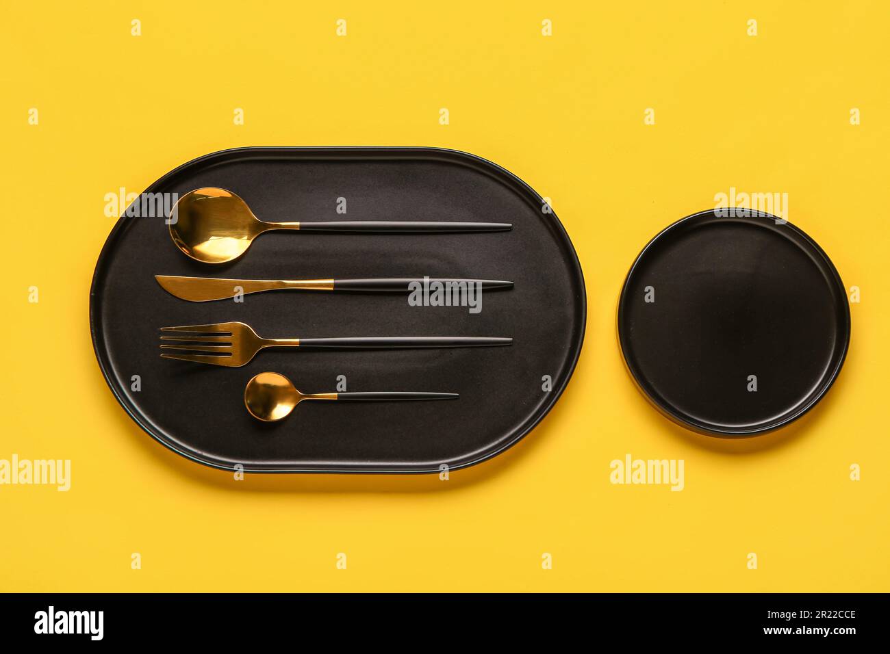 Table setting with clean plates and cutlery on yellow background Stock