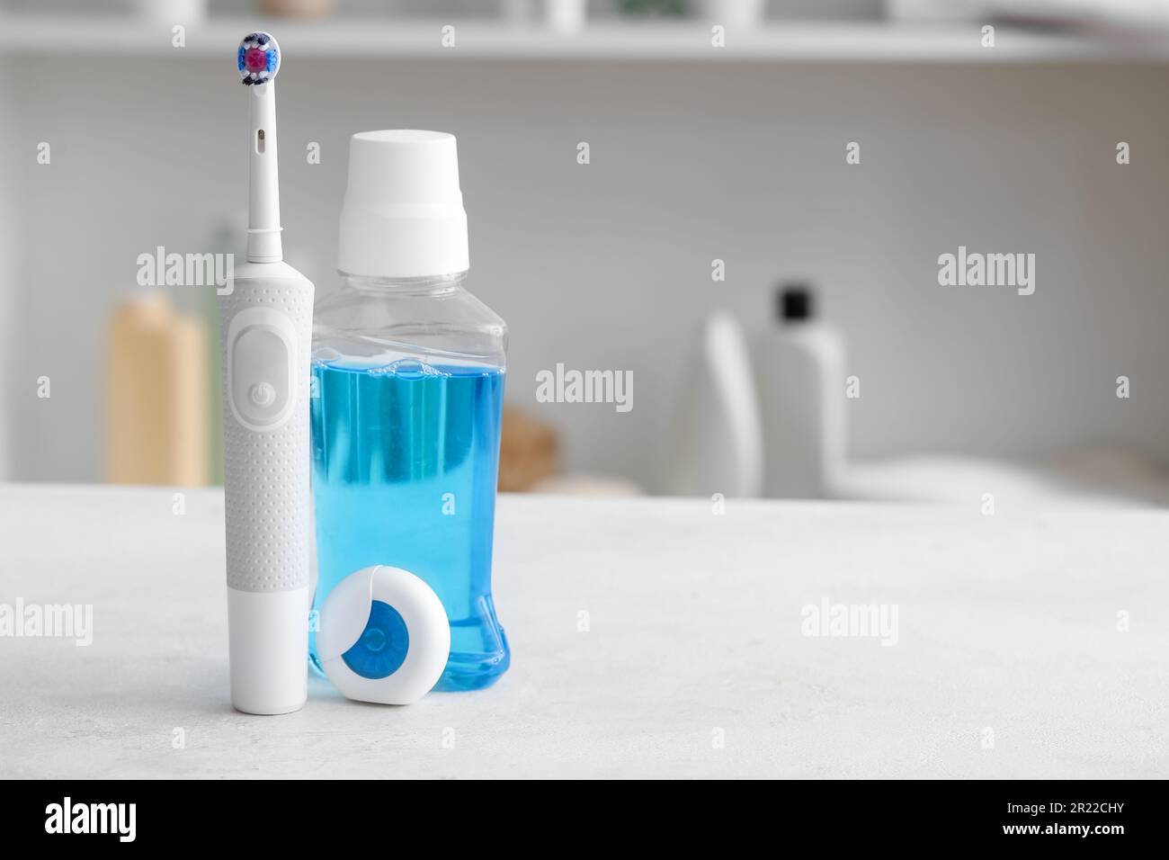 Dental floss with electrical toothbrush and mouthwash on white table in ...