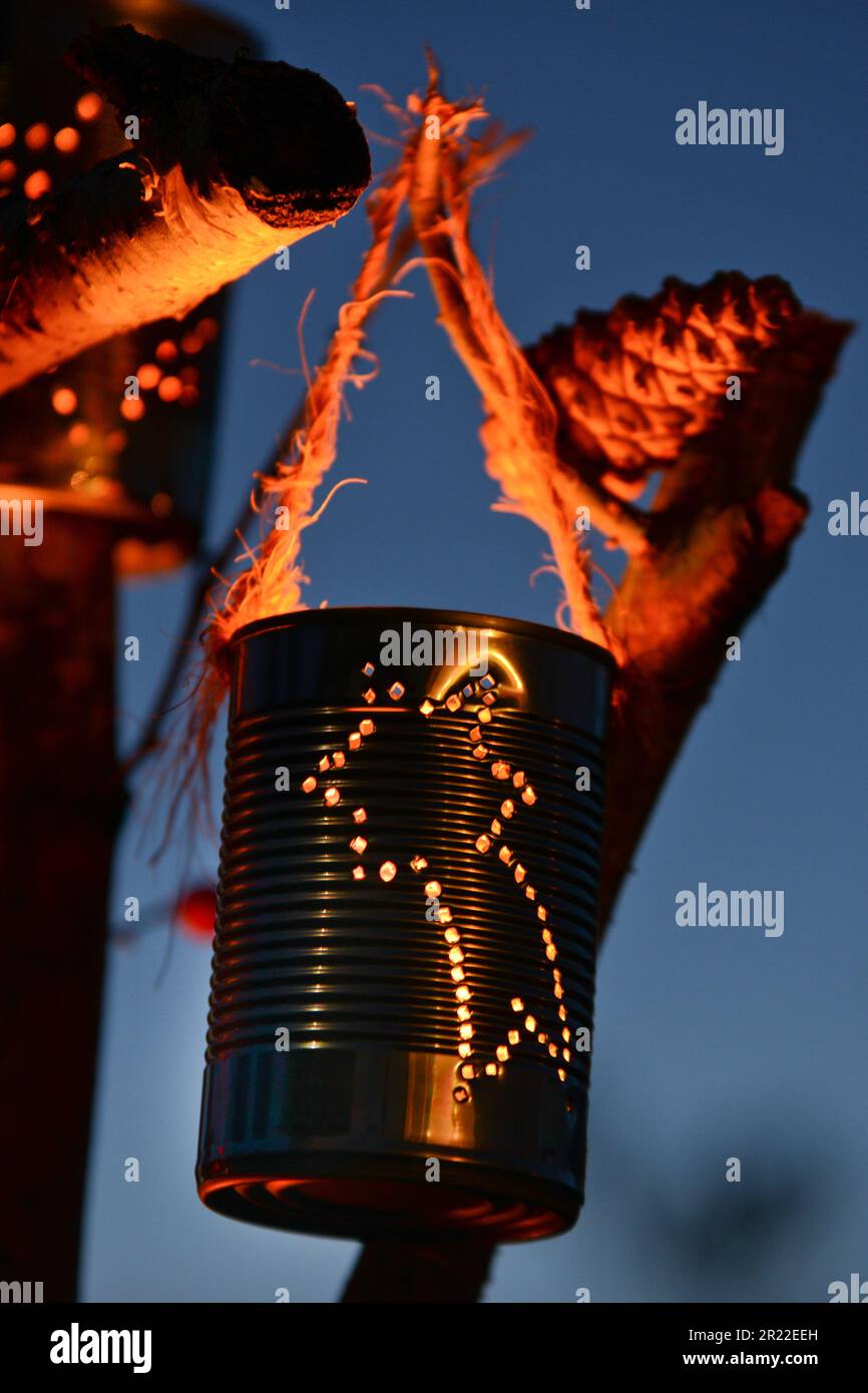 lantern made of tin cans hangind on branches, inside with bruning tea light Stock Photo