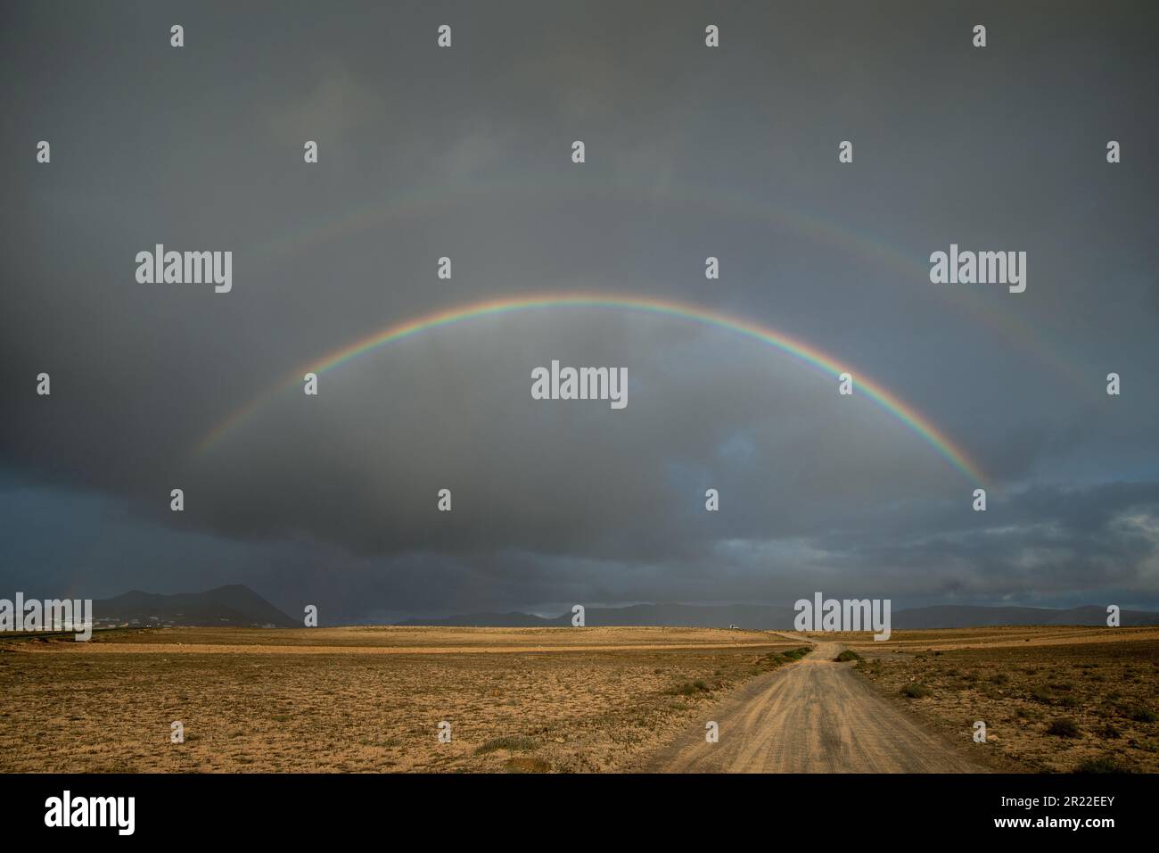 double rainbow over Soo and the sand plain El Jable, Canary Islands, Lanzarote Stock Photo