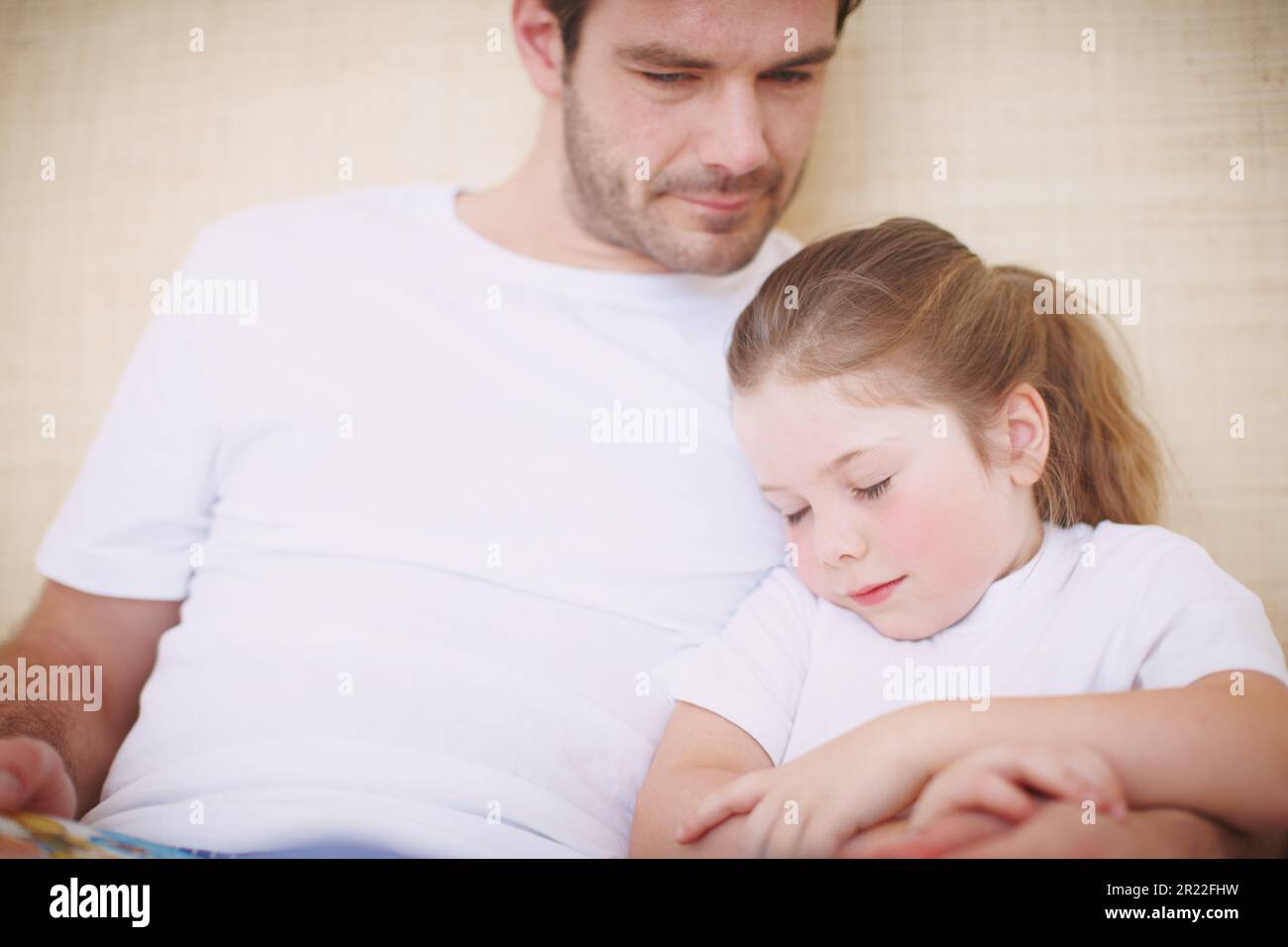 Falling asleep in her fathers arms. a devoted father siting with his