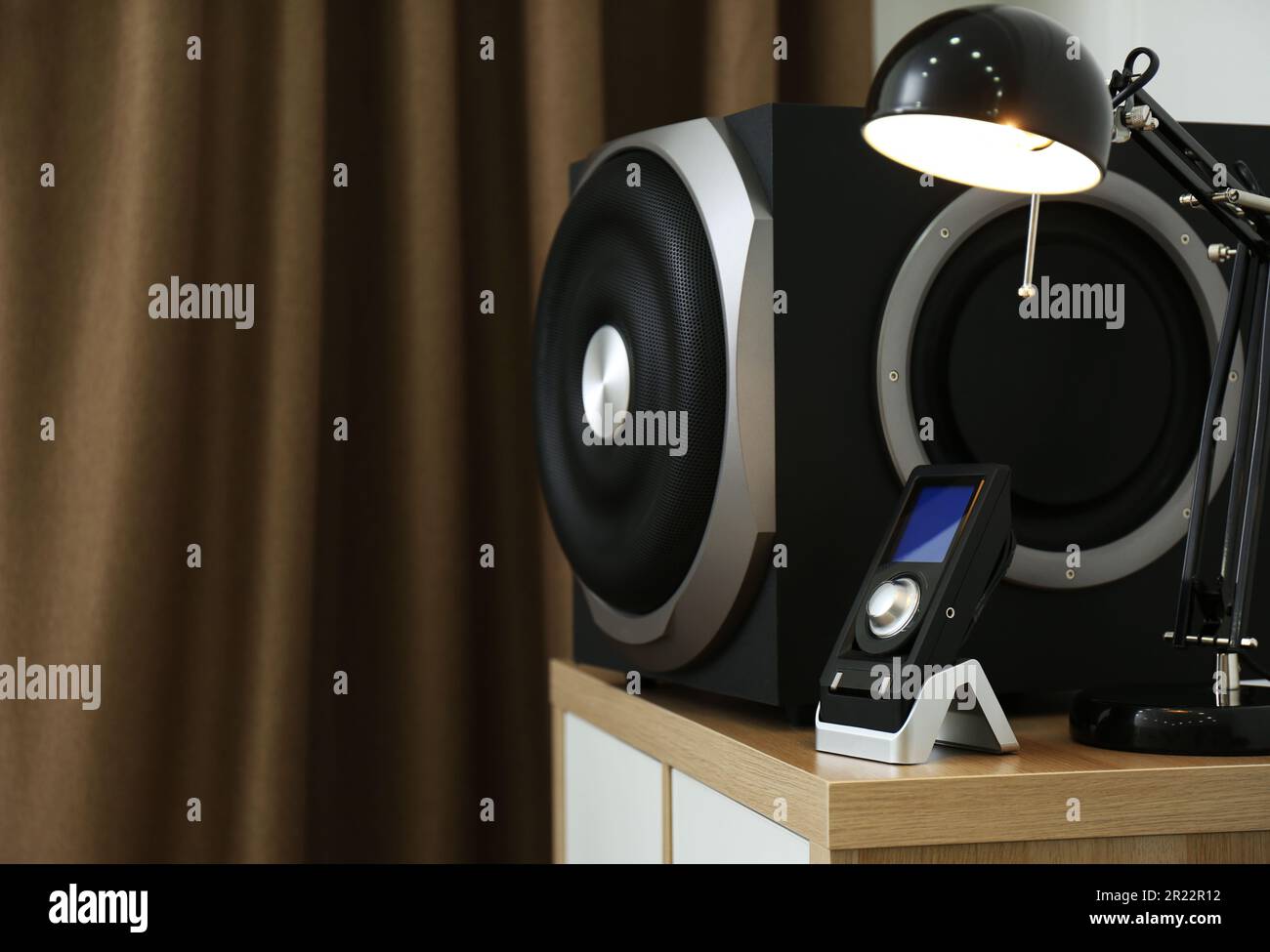 Modern subwoofer, remote and lamp on indoors, space for text