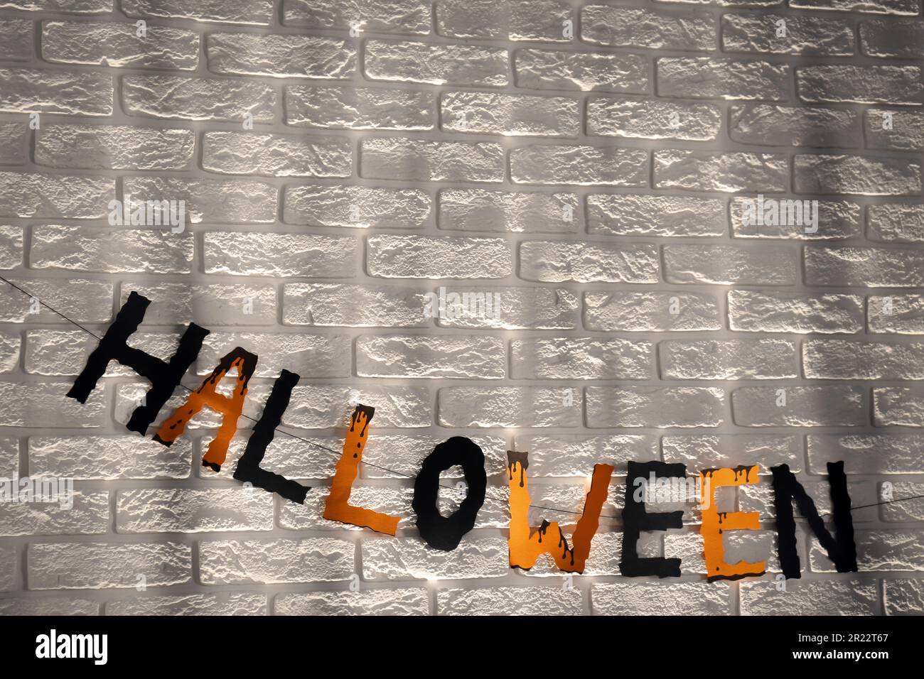 Word Halloween made of colorful letters on brick wall. Festive decor Stock Photo