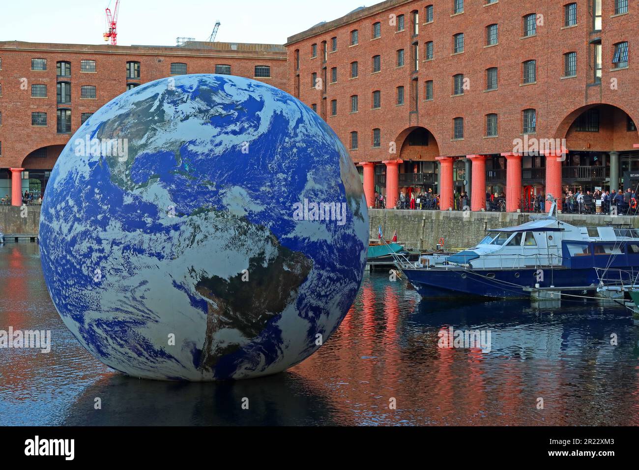 Luke Jerram Floating Earth comes to Liverpool's Royal Albert Dock, looking majestic on a sunset evening, in front of the Victorian port warehouses Stock Photo