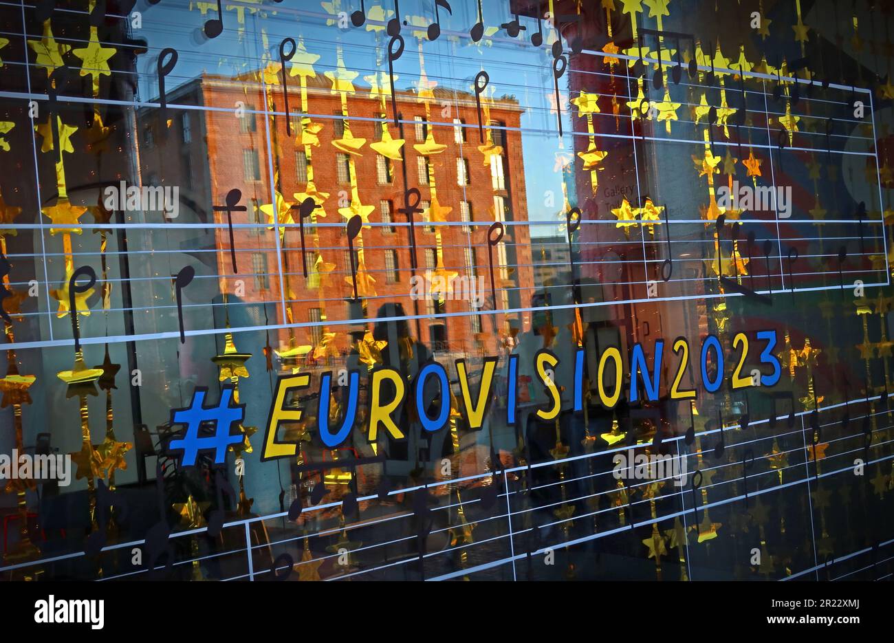 Eurovision2023 decorated shop window, with the Royal Albert Dock sunset reflected, Liverpool, Merseyside, England, UK, L3 4AF Stock Photo