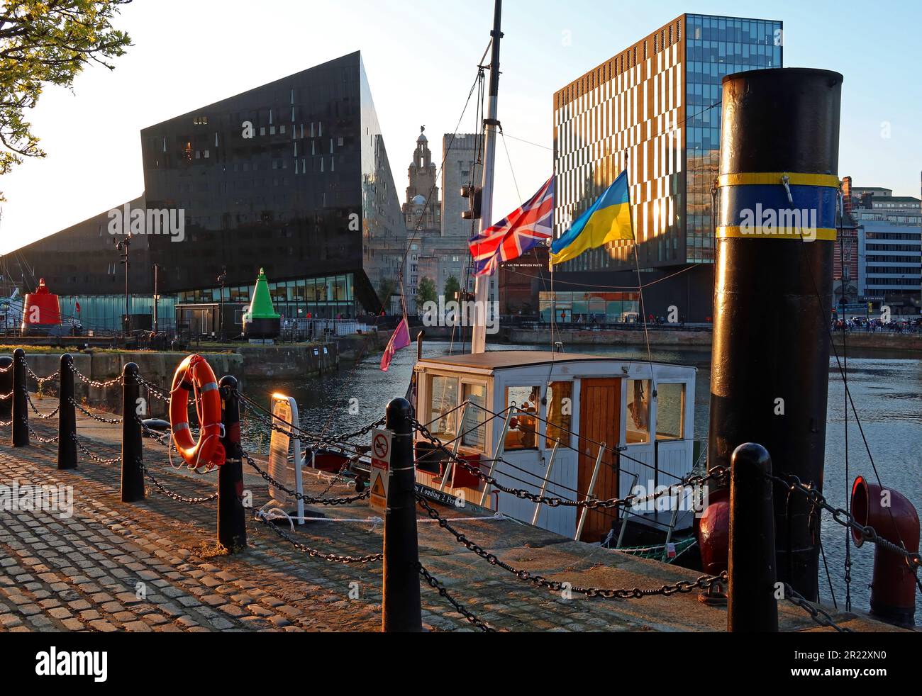 Royal Albert Dock, Mann Island at sunset, with steam tug and flags, Pier Head, Liverpool, Merseyside, England, UK, L3 4AF Stock Photo