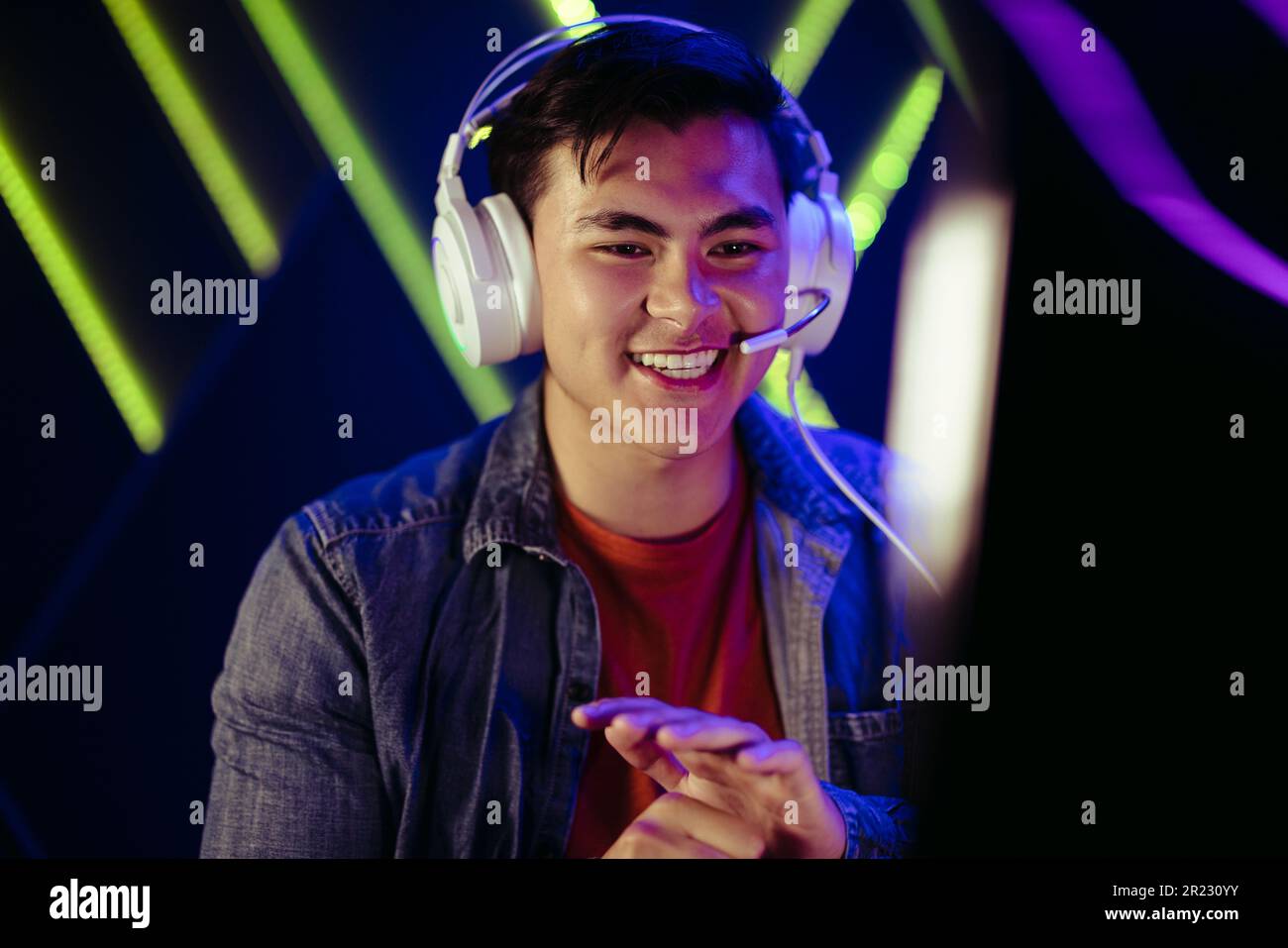 Male gamer smiling while looking at his computer screen, filled with pride and satisfaction after winning in a video game. Happy young man enjoying a Stock Photo