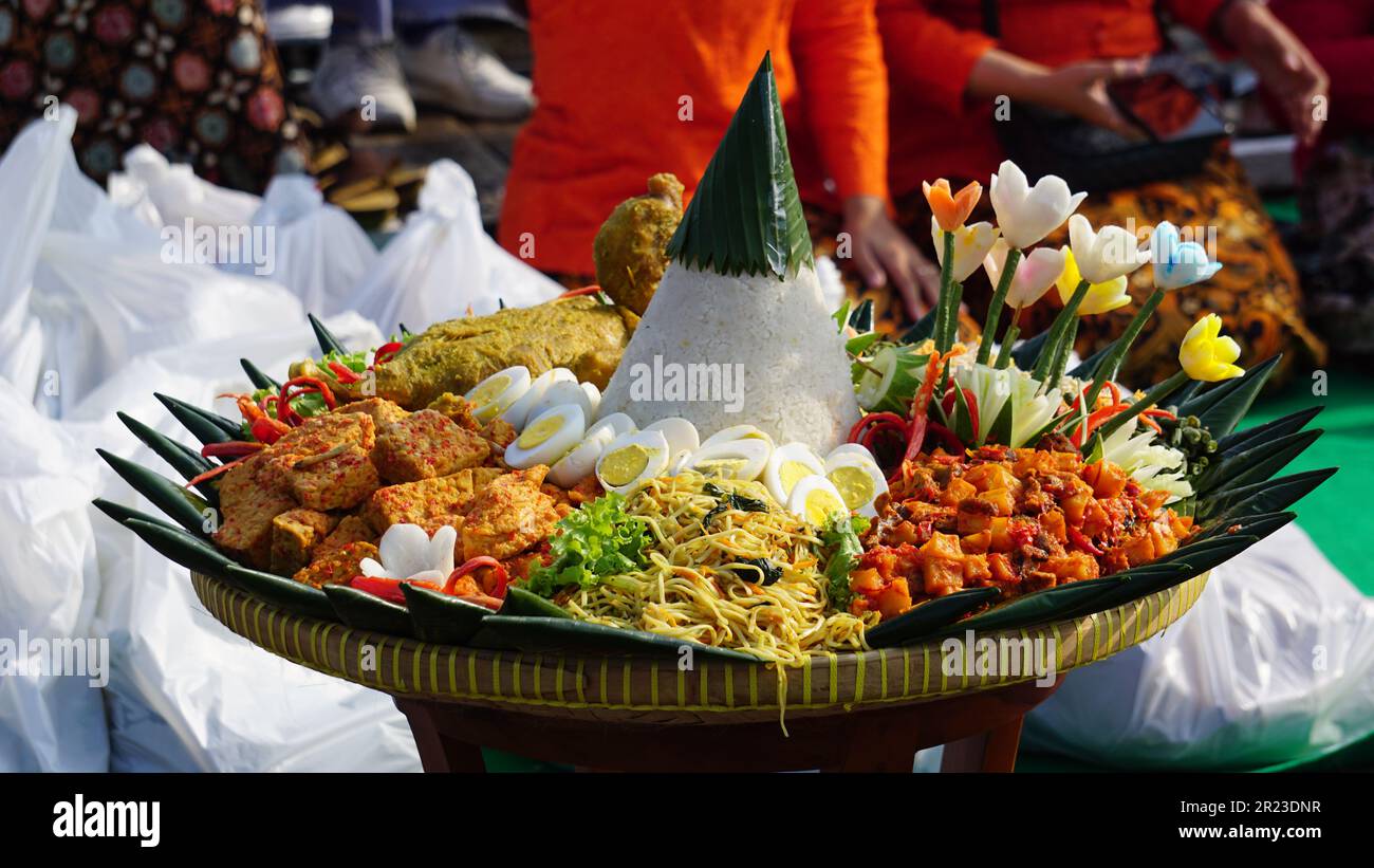 Nasi tumpeng (cone rice) served with urap-urap (Indonesian salad), fried chicken and noodles. Nasi tumpeng usually served at birthday parties Stock Photo