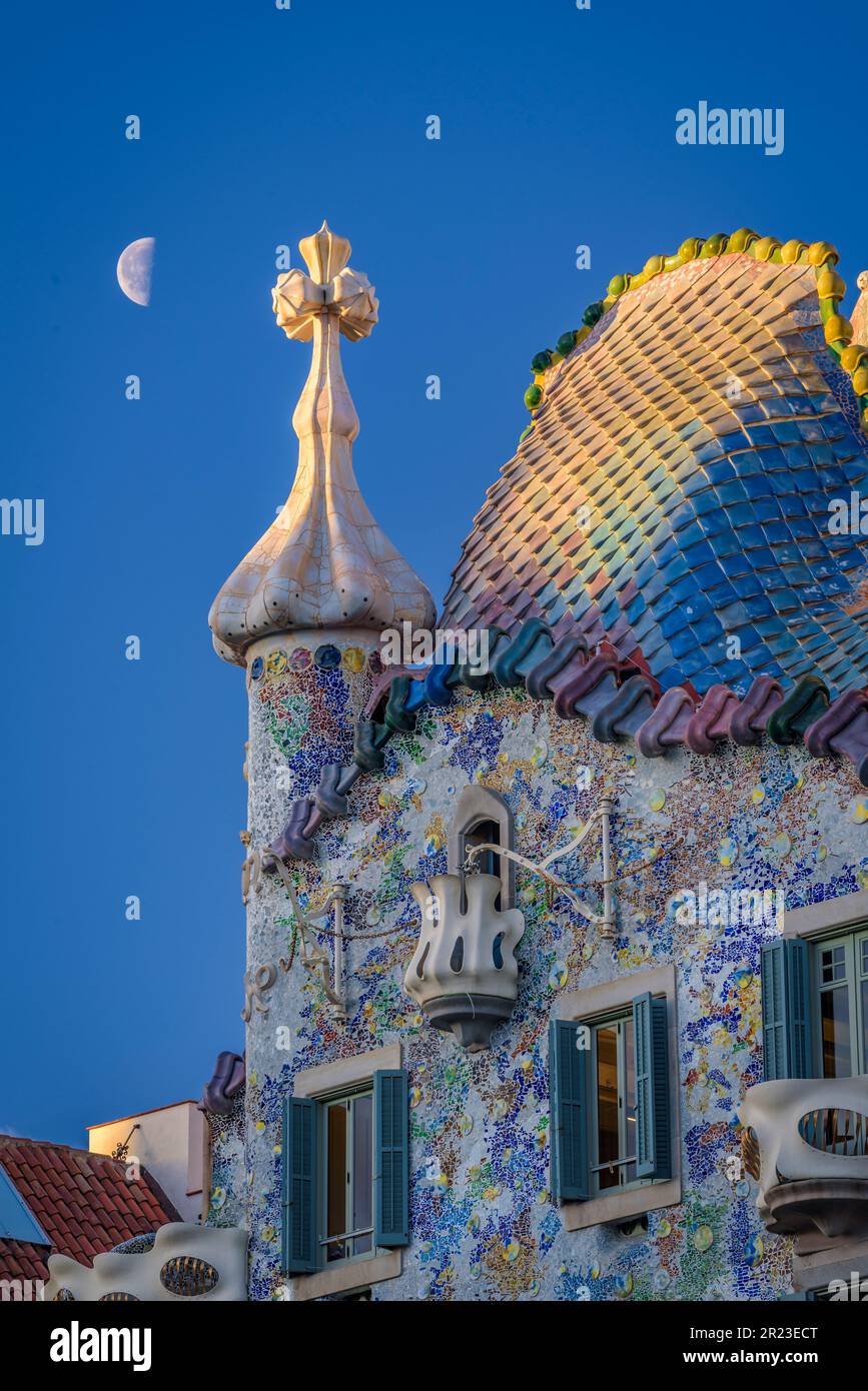 Sunrise over the roof of the Casa Batlló with the waning moon behind the cross of Saint George that crowns the façade (Barcelona, Catalonia, Spain) Stock Photo
