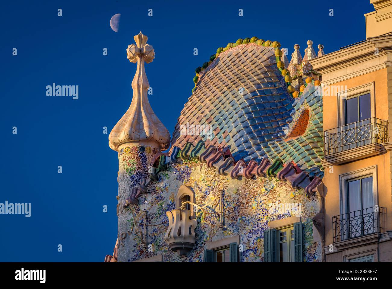 Sunrise over the roof of the Casa Batlló with the waning moon behind the cross of Saint George that crowns the façade (Barcelona, Catalonia, Spain) Stock Photo