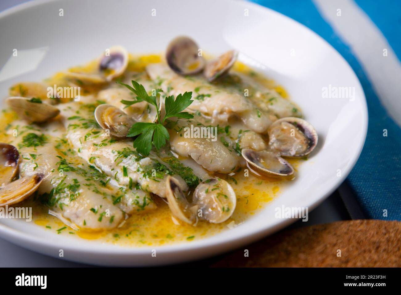 Blue whiting with green sauce. Traditional recipe from the Basque country in northern Spain. Stock Photo