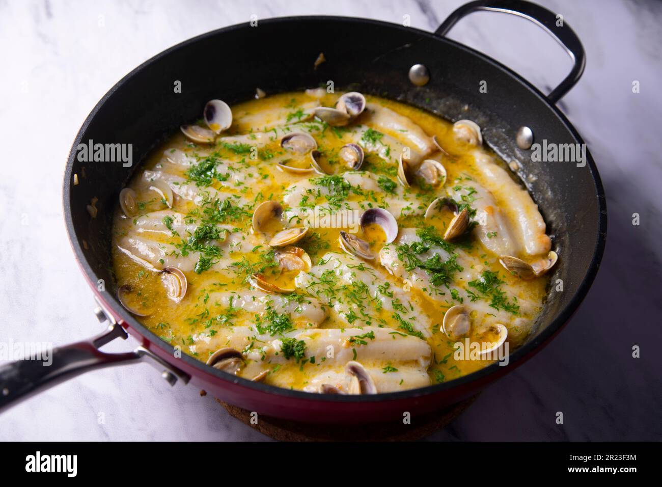 Blue whiting with green sauce. Traditional recipe from the Basque country in northern Spain. Stock Photo