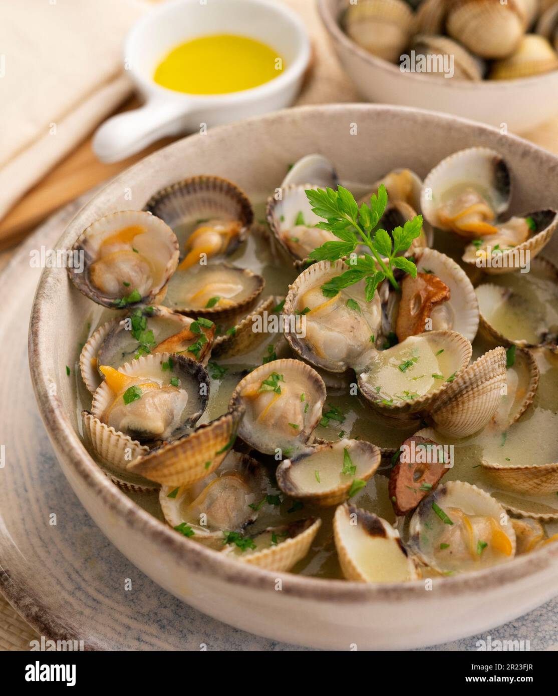 Cockles with green garlic and parsley sauce. Traditional Spanish fish tapa. Stock Photo