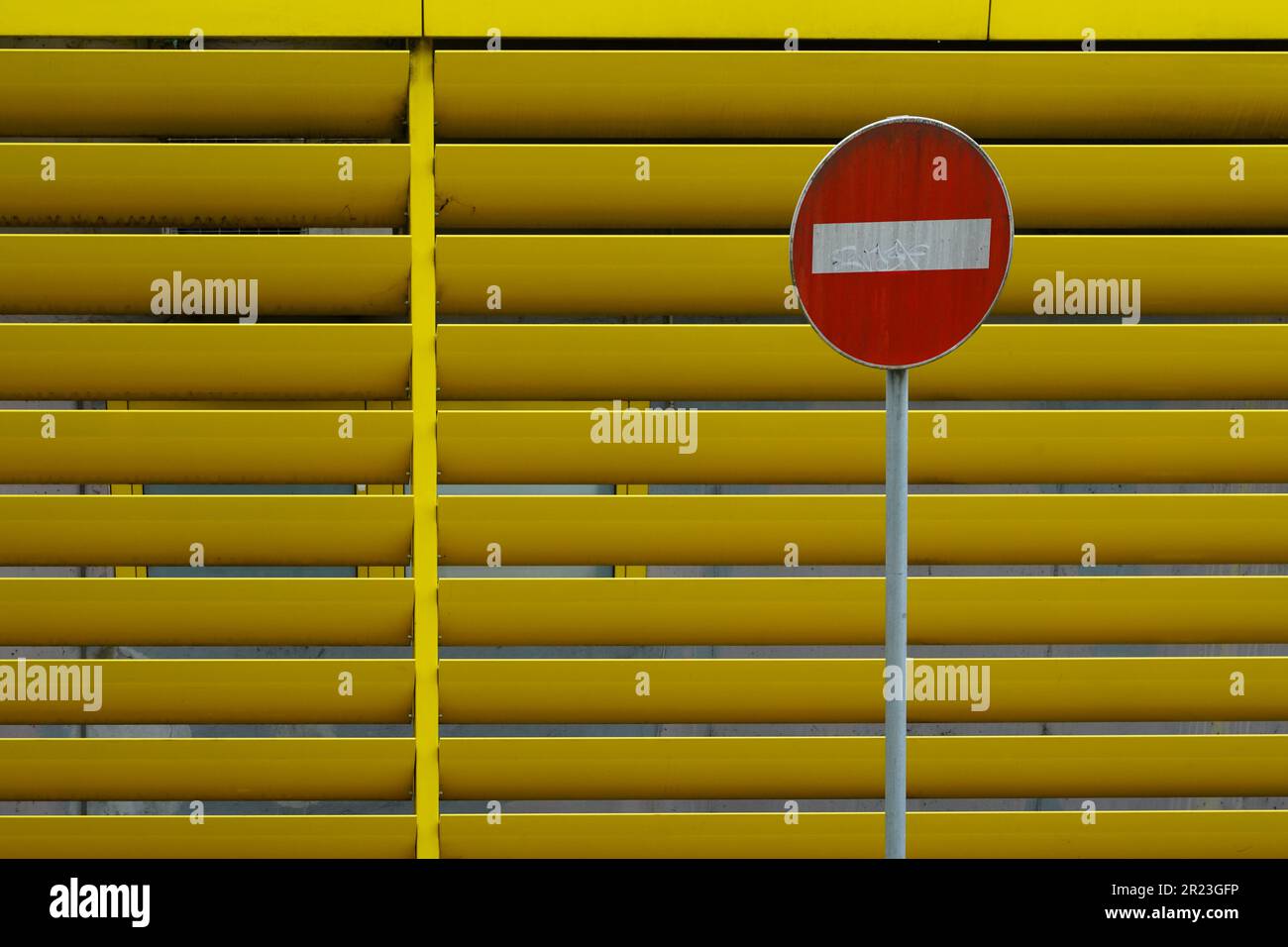 Oneway street sign in front of half open yellow blinds of a parking