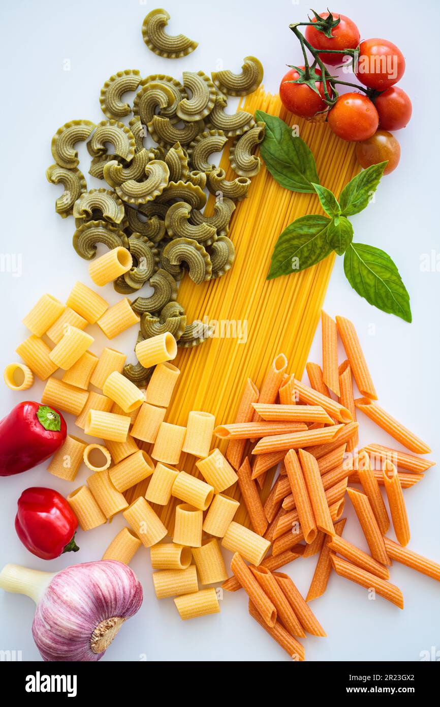 Different types of pasta with ingredients on white background, flat lay