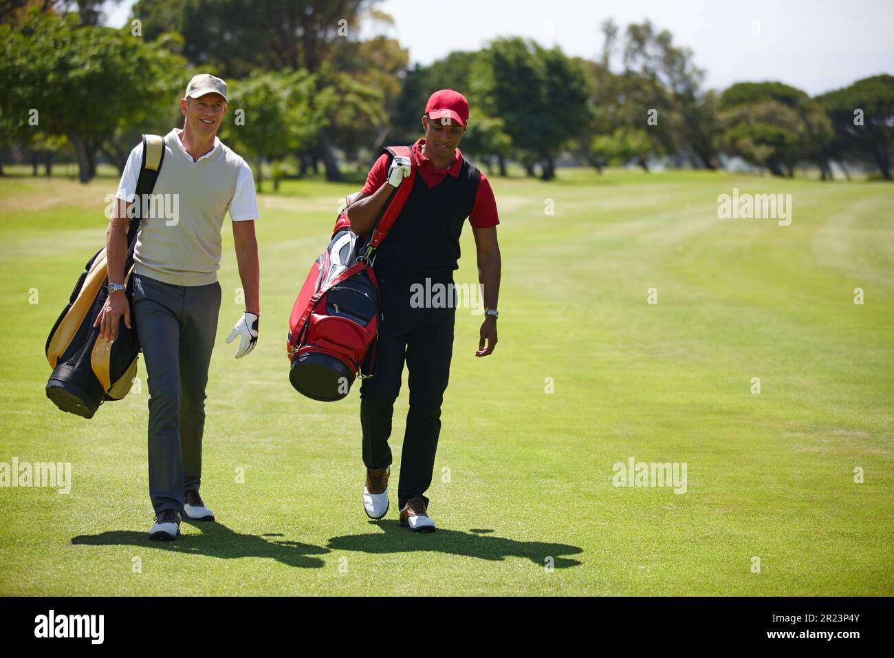 Bonding on the green. two men carrying their golf bags across a golf course. Stock Photo