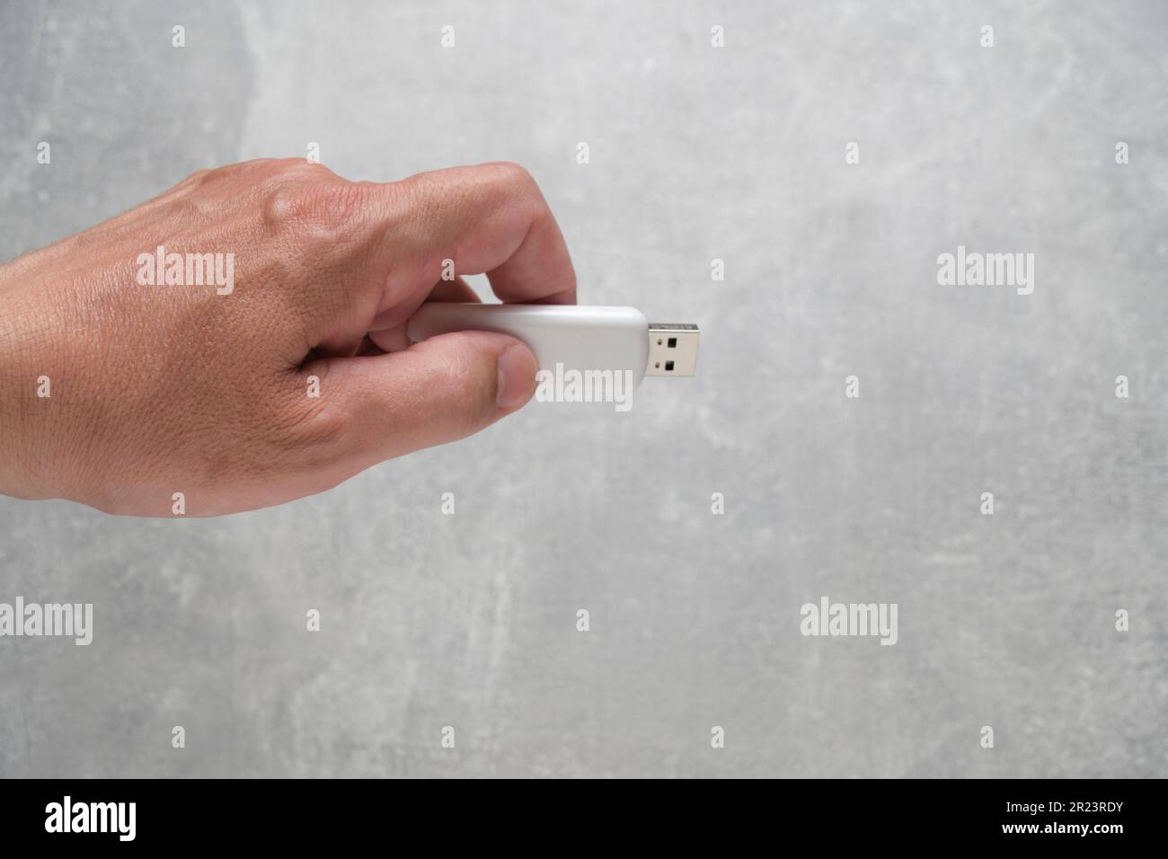 Man hand holds USB flash drive, on gray background Stock Photo