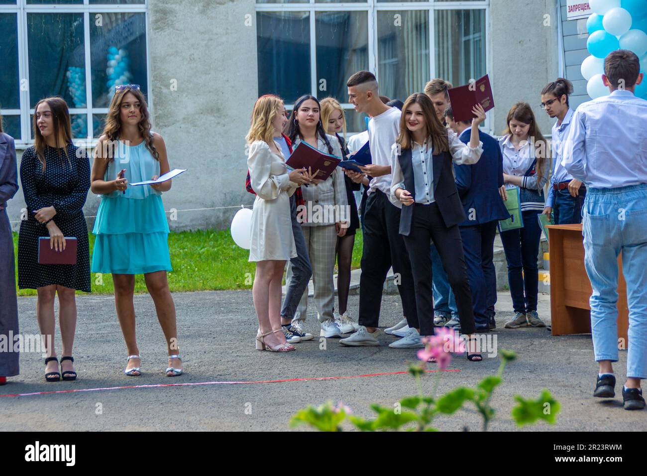 Russia, Kemerovo - 07, 2021. Outdoors, graduates of an educational institution receive a document of graduation, a young woman rejoices at receiving a Stock Photo