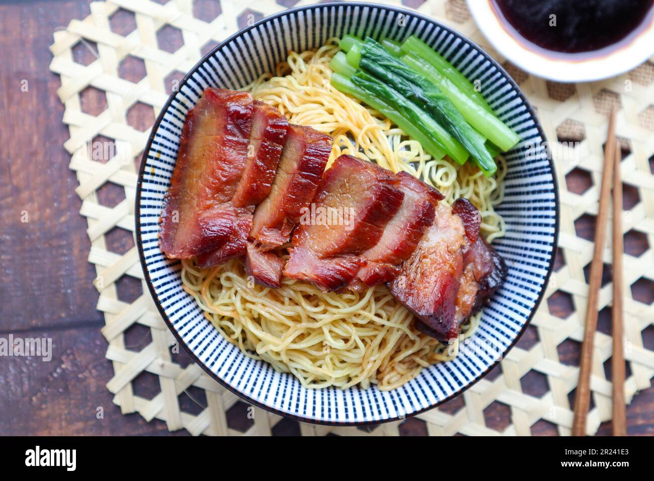 Chinese barbecue roast pork noodle (Char Siu) in a bowl on bamboo