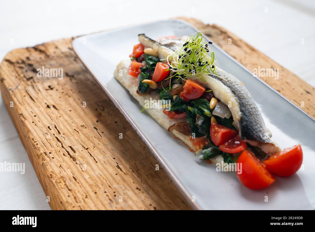 Baked sea bass fillet stuffed with spinach, pine nuts and cherry