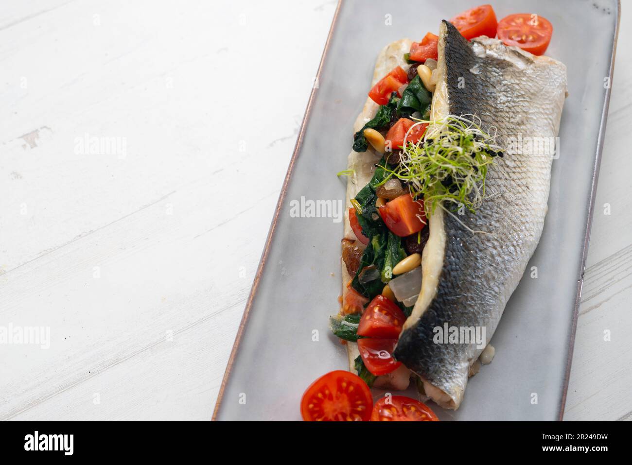 Baked sea bass fillet stuffed with spinach, pine nuts and cherry