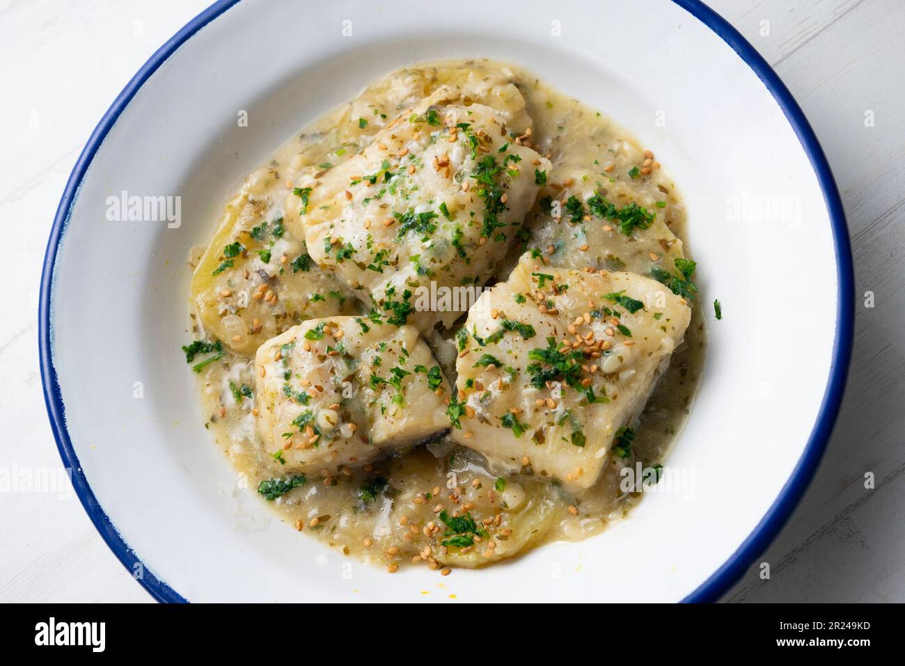 Hake cooked with green parsley and garlic sauce served with clams