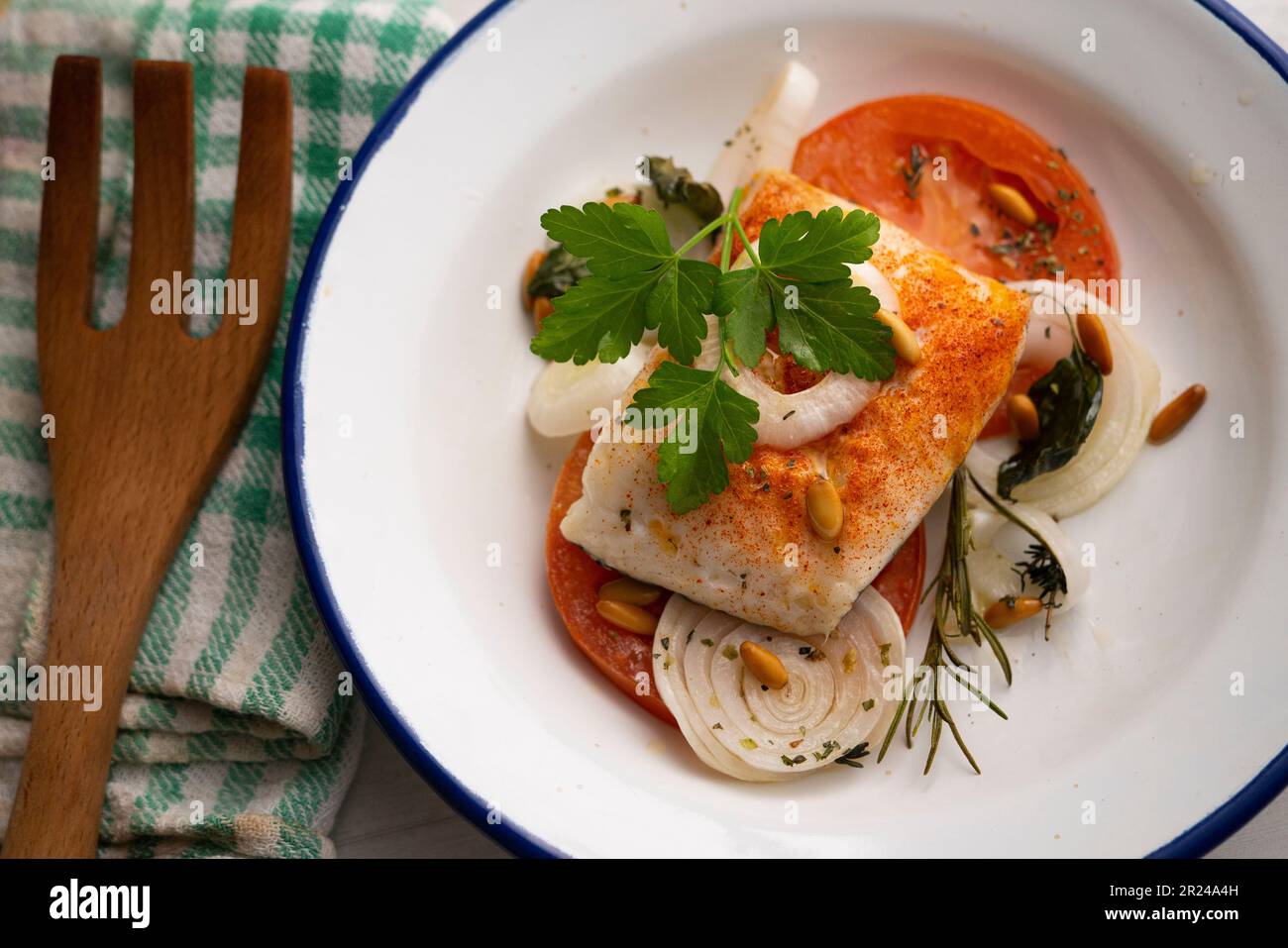 Baked hake fillet cooked with tomato and onion. Traditional Spanish