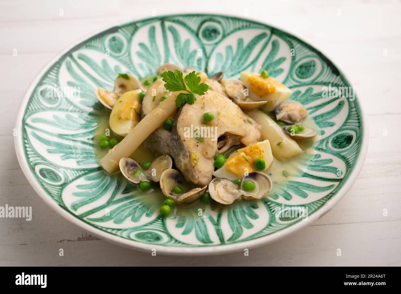 Basquestyle hake cooked with green parsley and garlic sauce, served