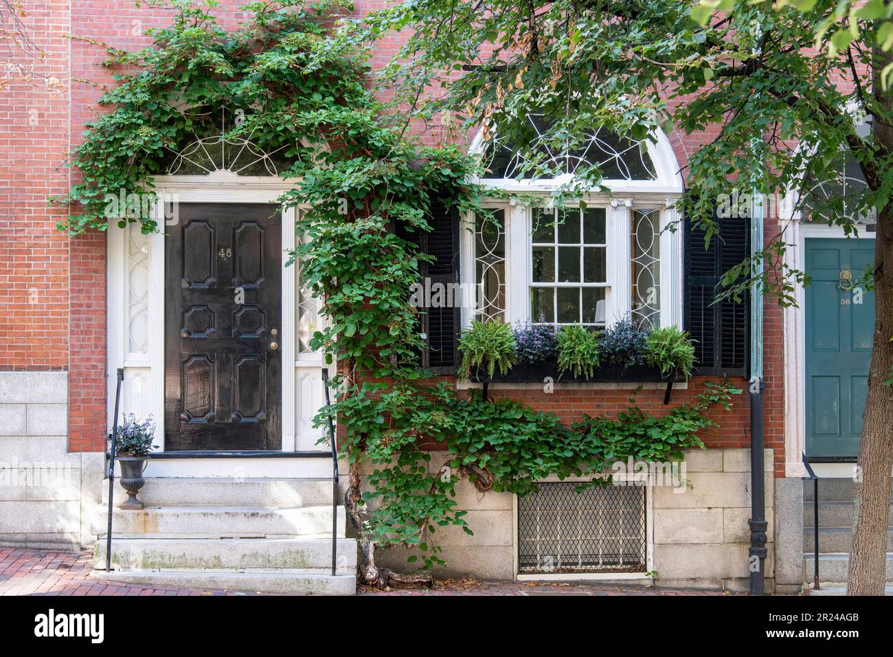 Boston, MA, USA-August 2022; Close up façade with stairs, door and window of a home in Beacon Hill neighborhood with Colonial Revival Stock Photo