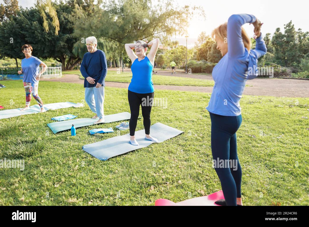 Multiracial senior people doing workout exercises outdoor with city park in background - Healthy lifestyle and joyful elderly lifestyle concept - Focu Stock Photo