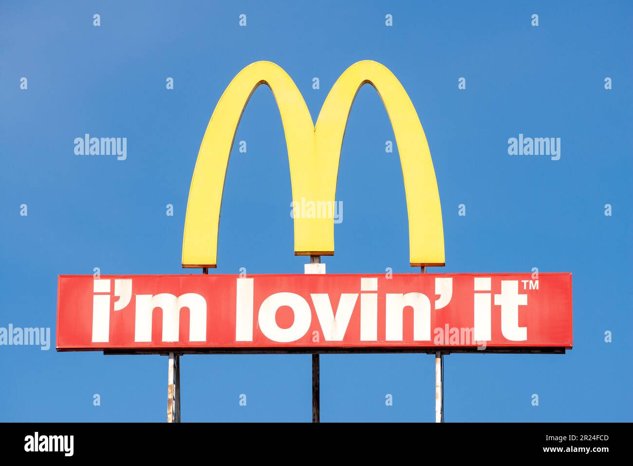 McDonald's logo arches sign and I'm Lovin' It slogan against blue sky with copy space Stock Photo