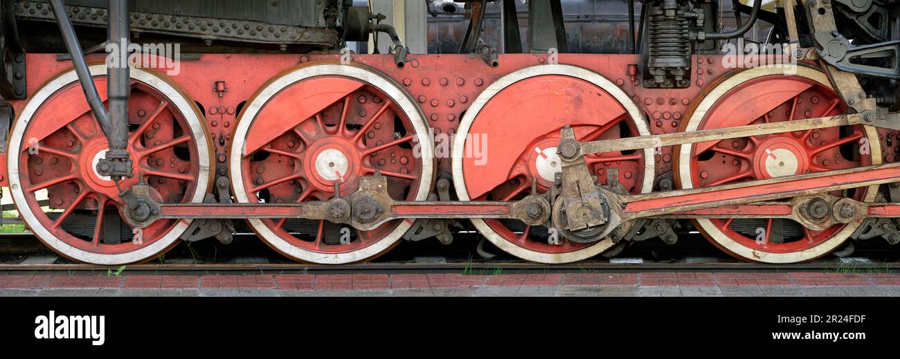 Big red wheels, flywheels, connecting rods and other machinery of an old steam locomotive. Stock Photo