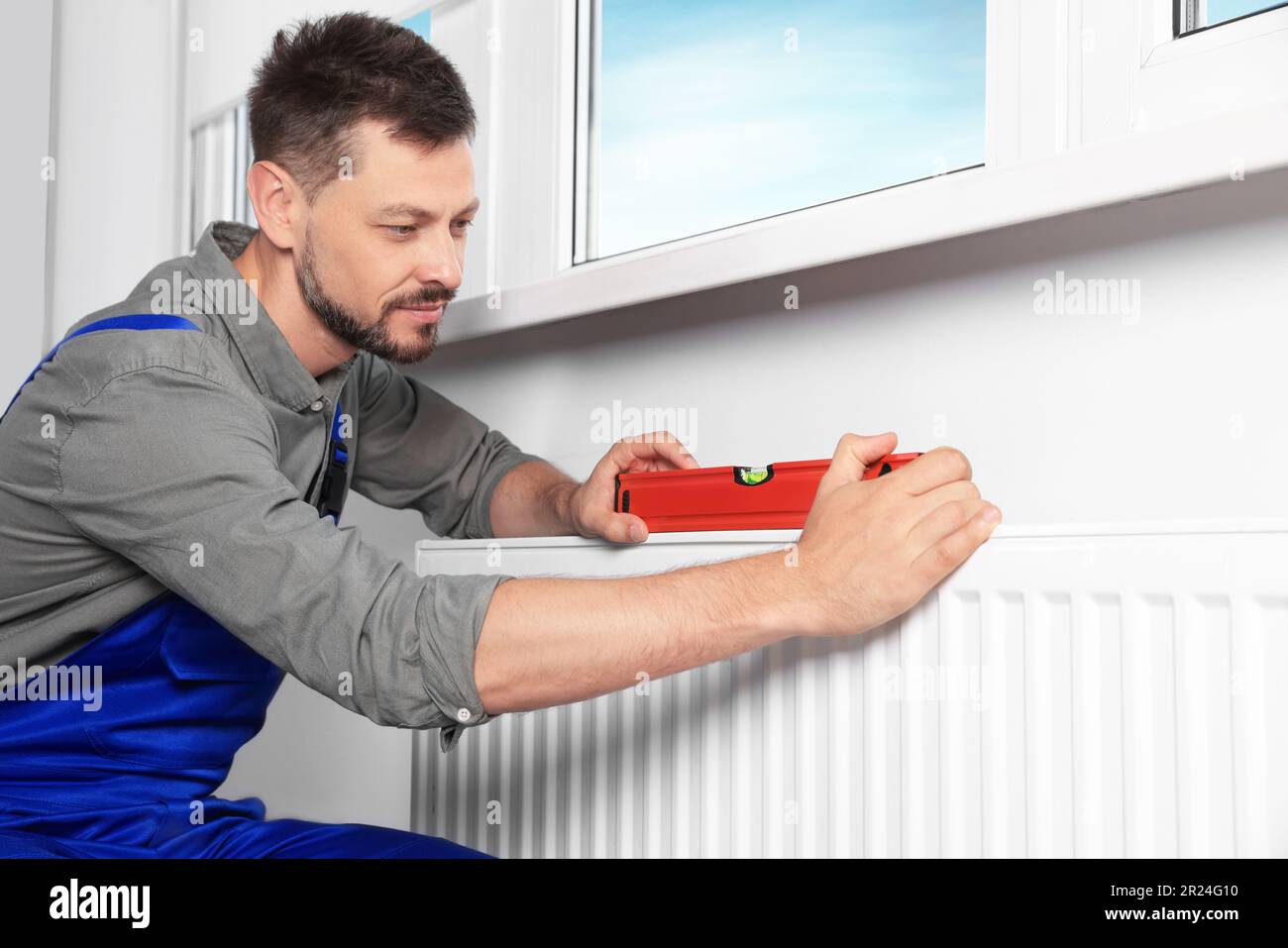 Professional plumber using bubble level for installing new heating ...
