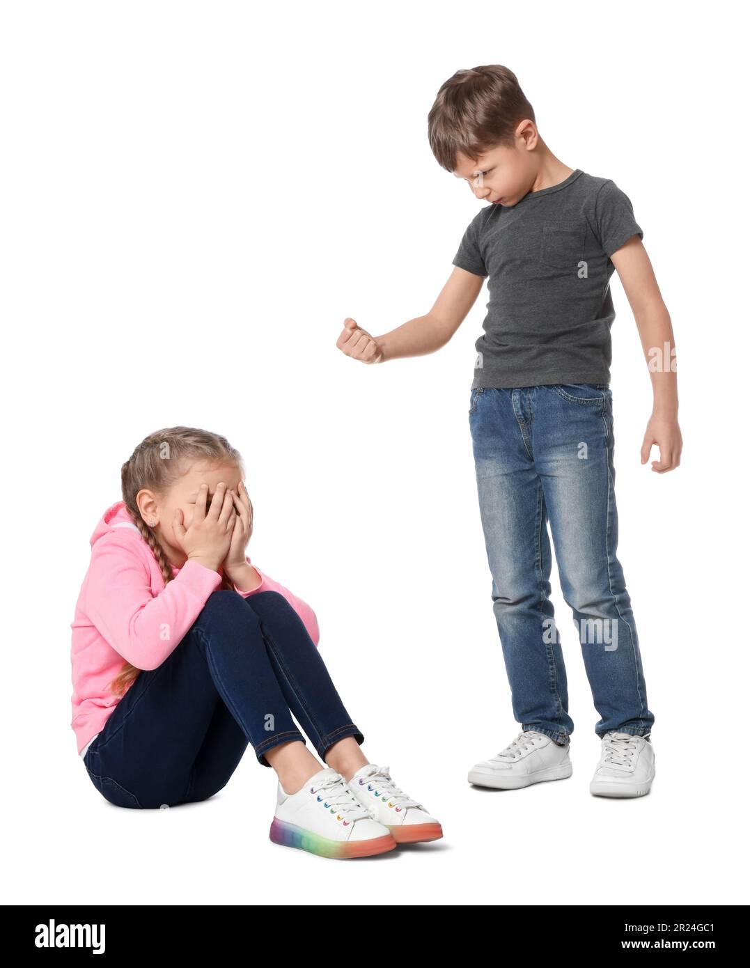 Boy with clenched fist looking at scared girl on white background. Children's bullying Stock Photo