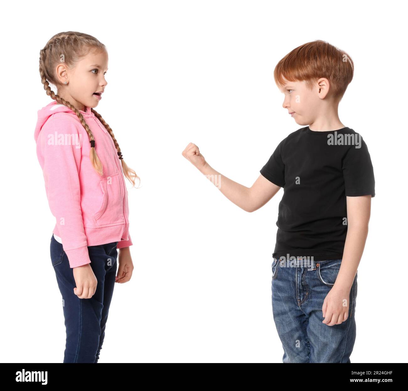 Boy with clenched fist looking at girl on white background. Children's bullying Stock Photo