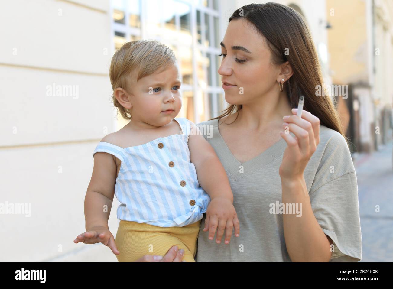 Mother with cigarette and child outdoors. Don't smoke near kids Stock