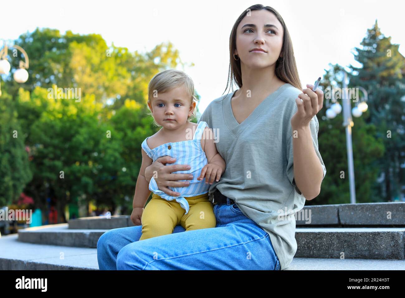 Mother with cigarette and child outdoors. Don't smoke near kids Stock