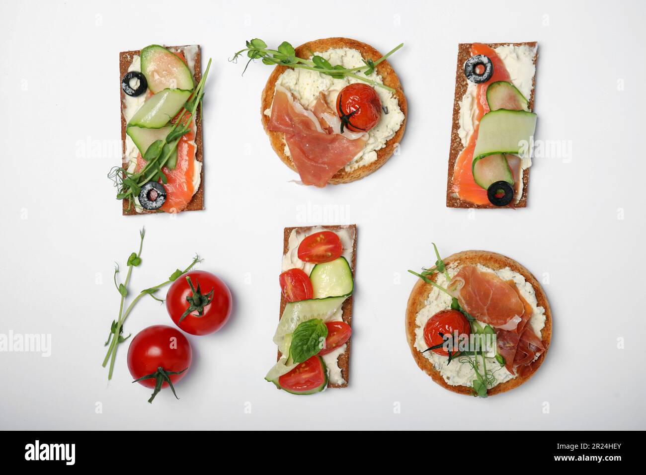 Tasty rusks and rye crispbreads with different toppings on white ...
