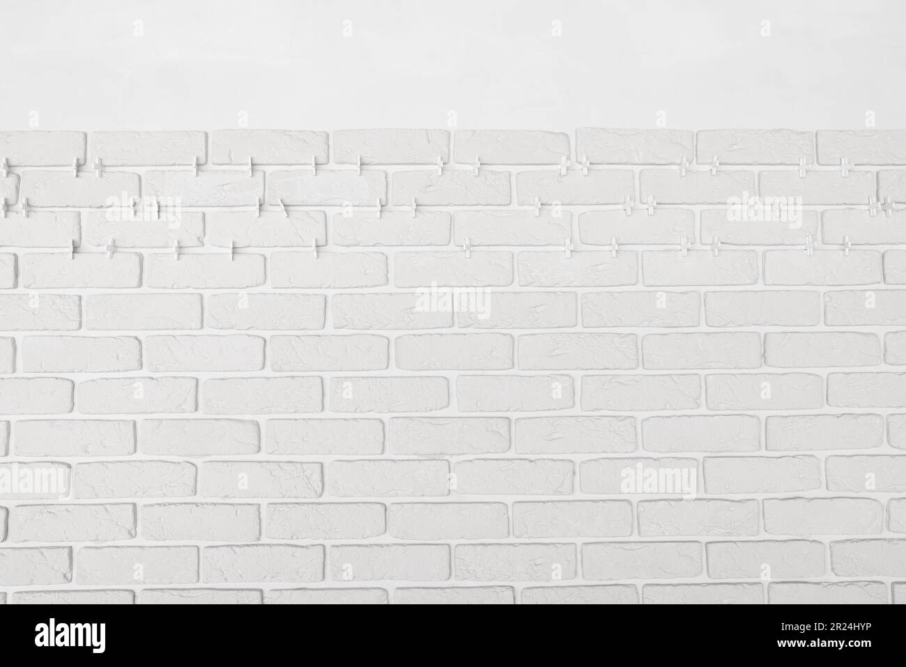 Decorative white bricks with tile leveling system on wall Stock Photo