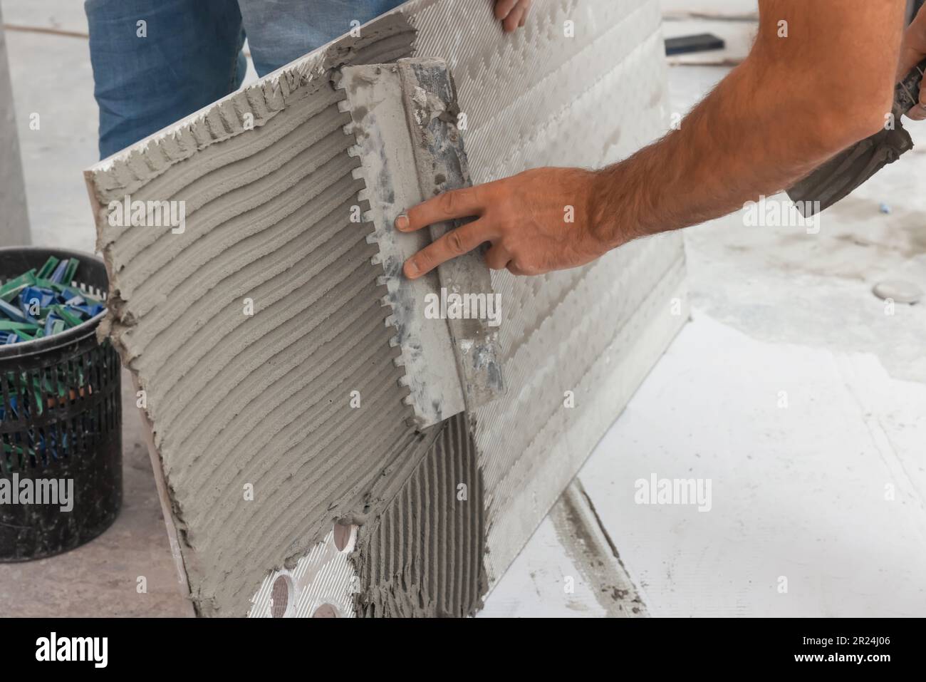 Worker spreading adhesive mix over tile with spatula, closeup Stock Photo