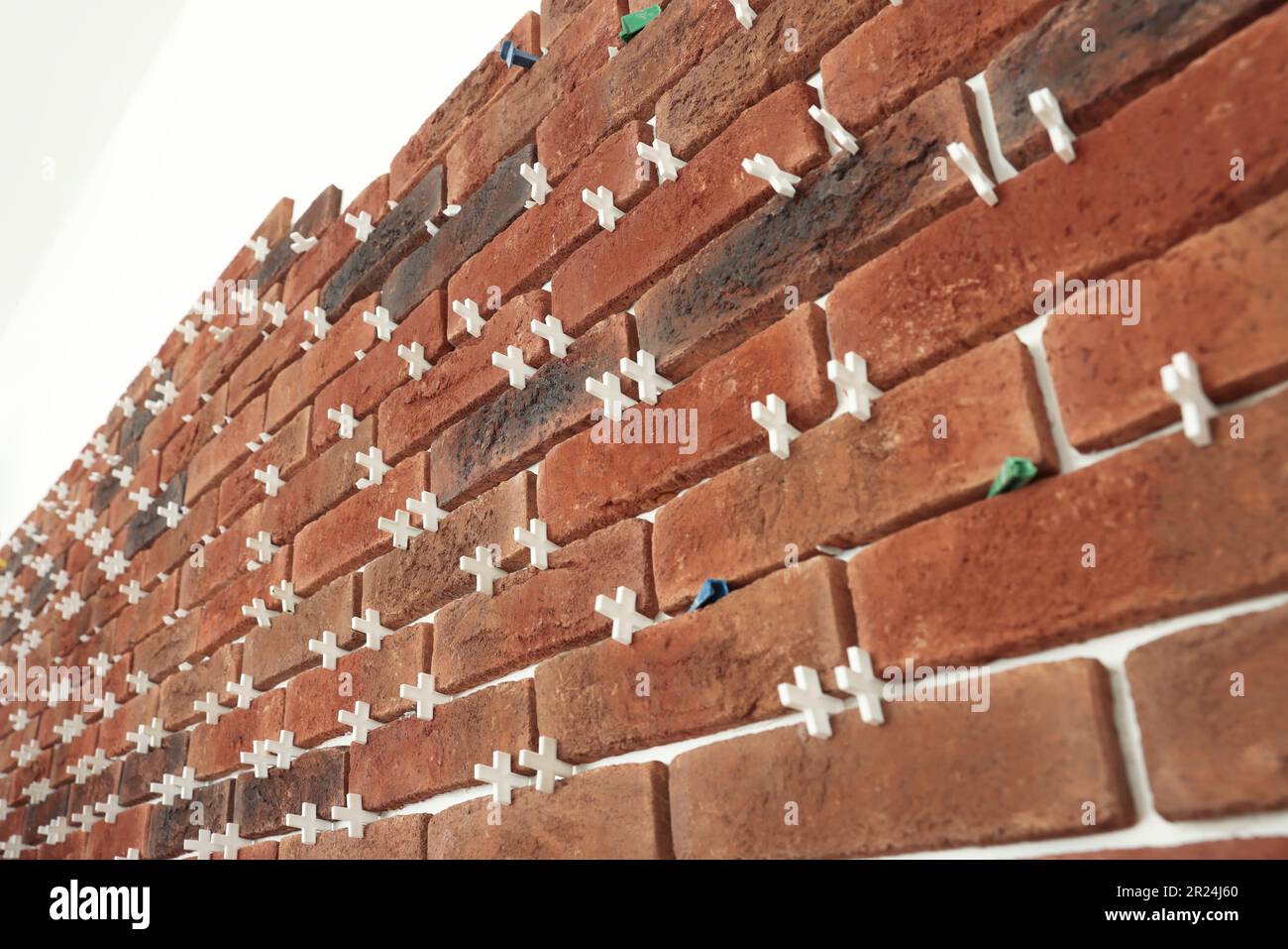 Decorative bricks with tile leveling system on white wall Stock Photo
