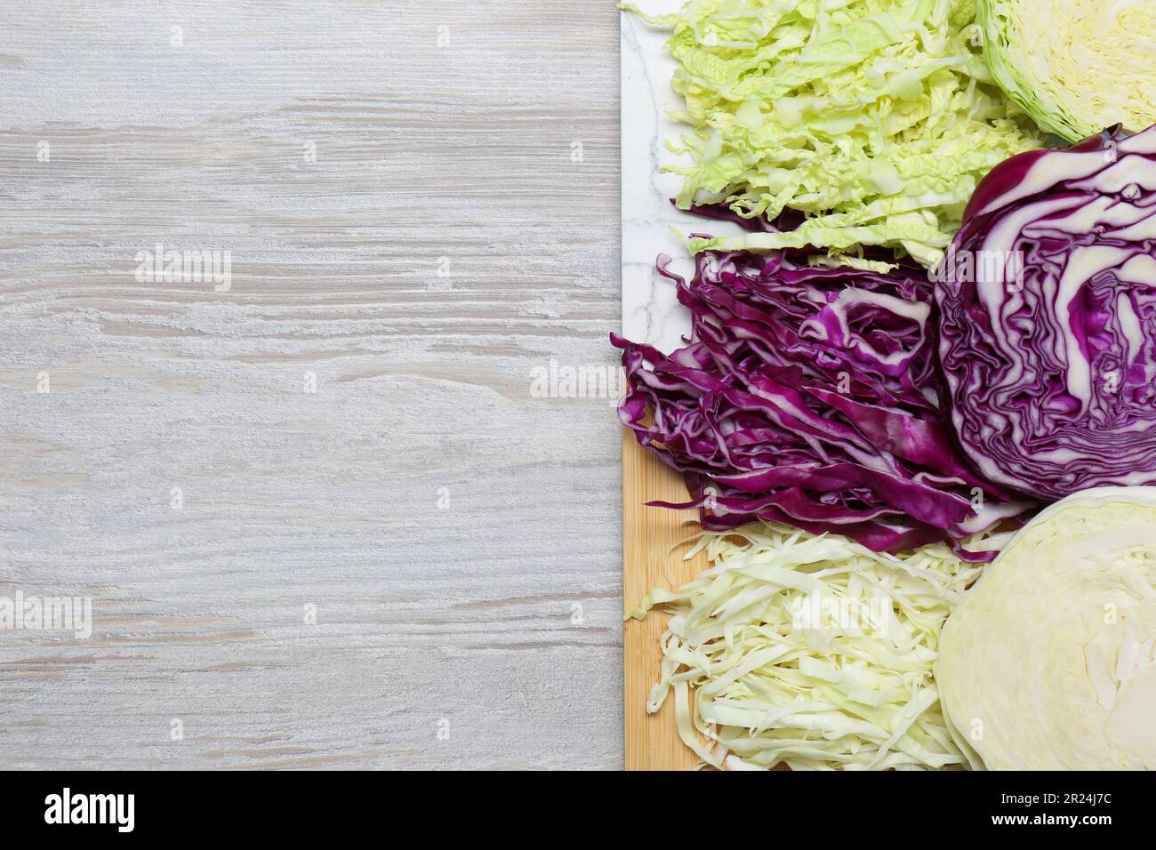 Different types of cut cabbage on white wooden table, top view. Space ...
