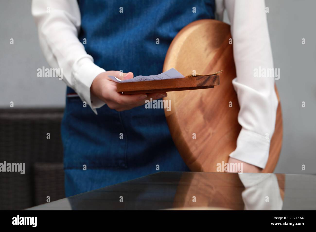 Waitress holding wooden tray with tips and receipt in cafe, closeup Stock Photo