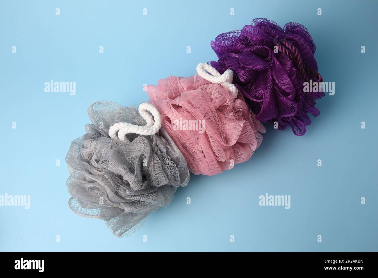 Colorful shower puffs on light blue background, flat lay Stock Photo