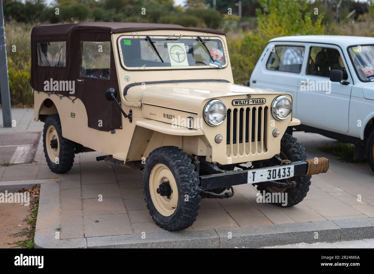 Detail of an old sand colored Jeep Willys parked in the street Stock
