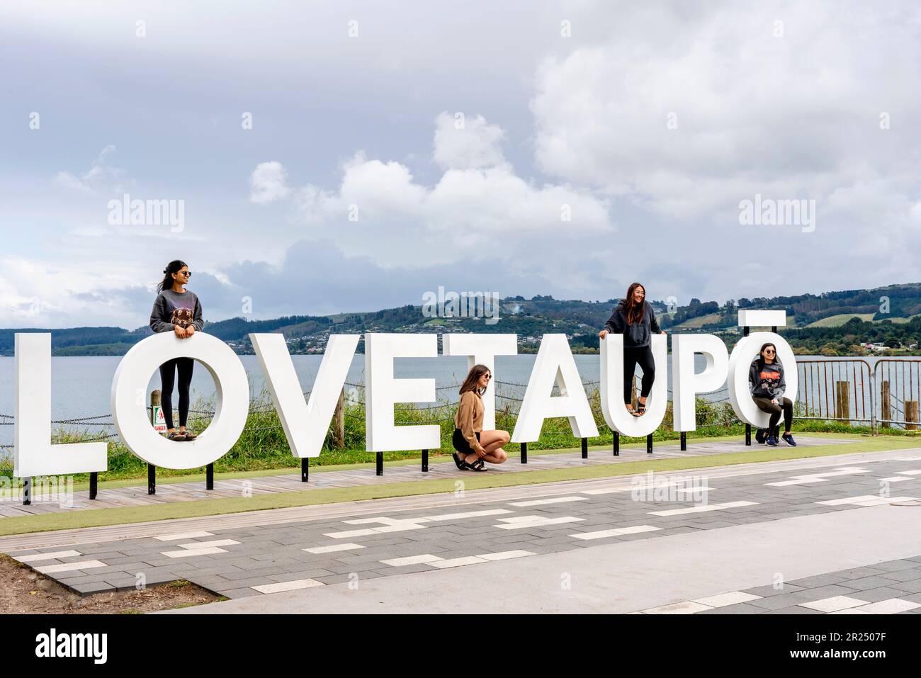 People Pose For Photos At The 'Love Taupo' Sign, Lake Taupo, North Island, New Zealand. Stock Photo
