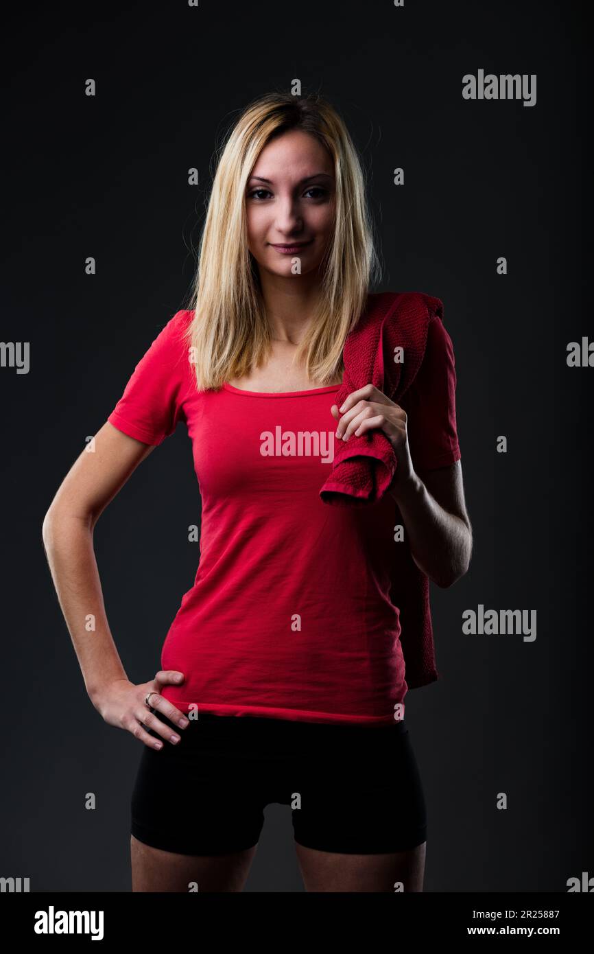 Portrait of a girl in gym attire: red t-shirt, black leggings. Effort ...