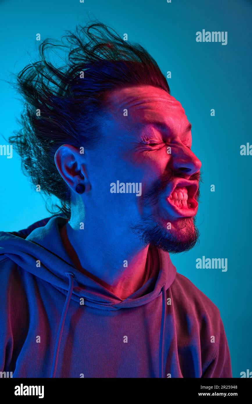 Funny portita of man posing with wind blowing into face against blue studio  background in neon light Stock Photo - Alamy