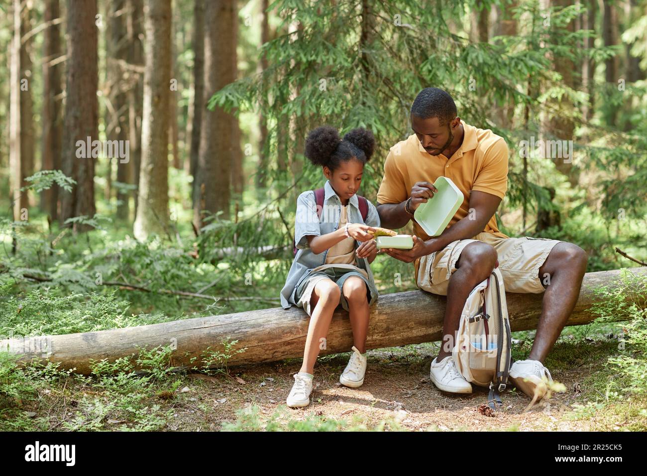 African American dad having snack together with his daughter while they ...
