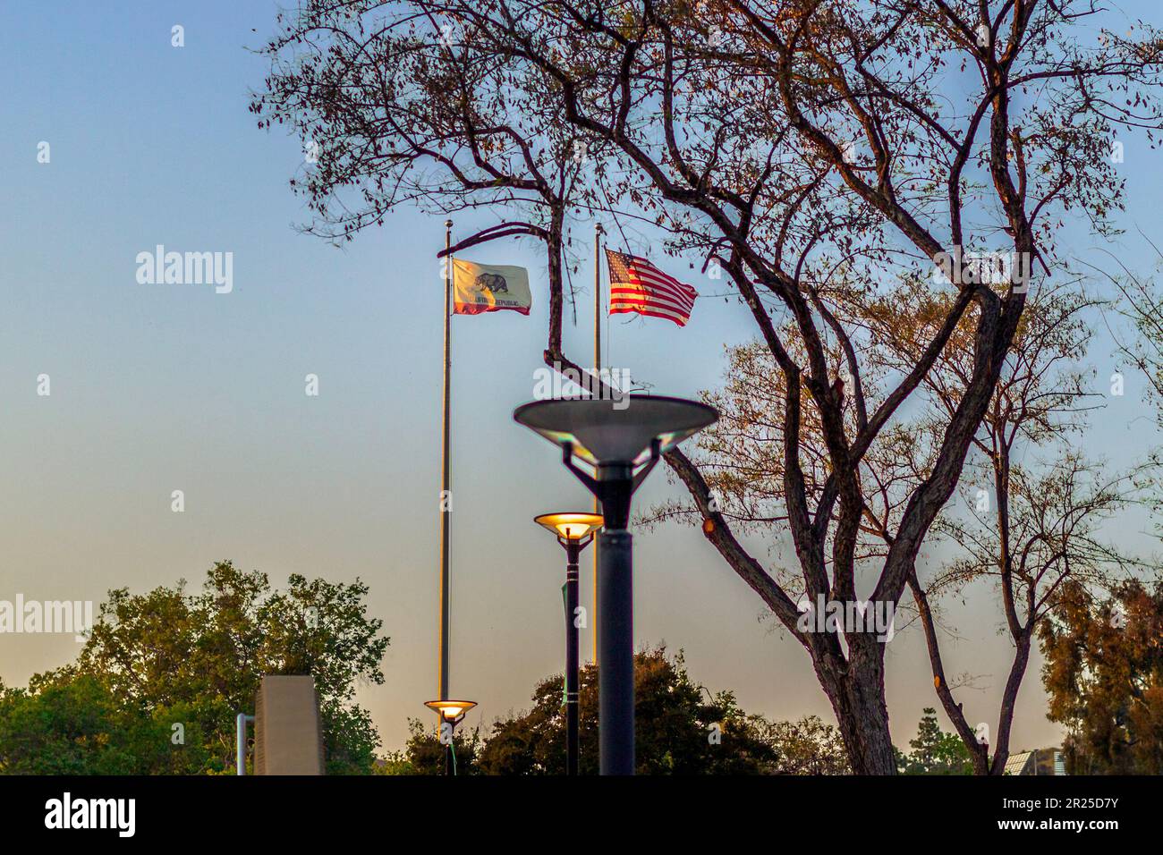 An inspiring golden hour image of the US and California flags waving in the wind high on a flagpole at Crafton Hills College. Stock Photo